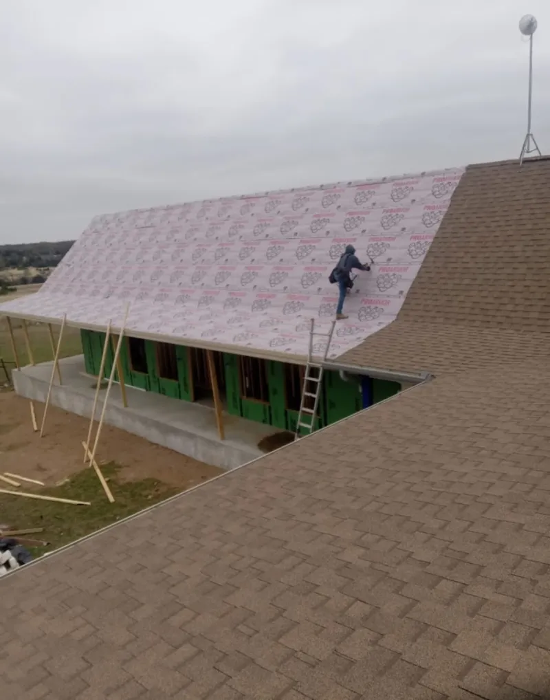 Worker preparing underlayment for a metal roof installation in Kinderhook